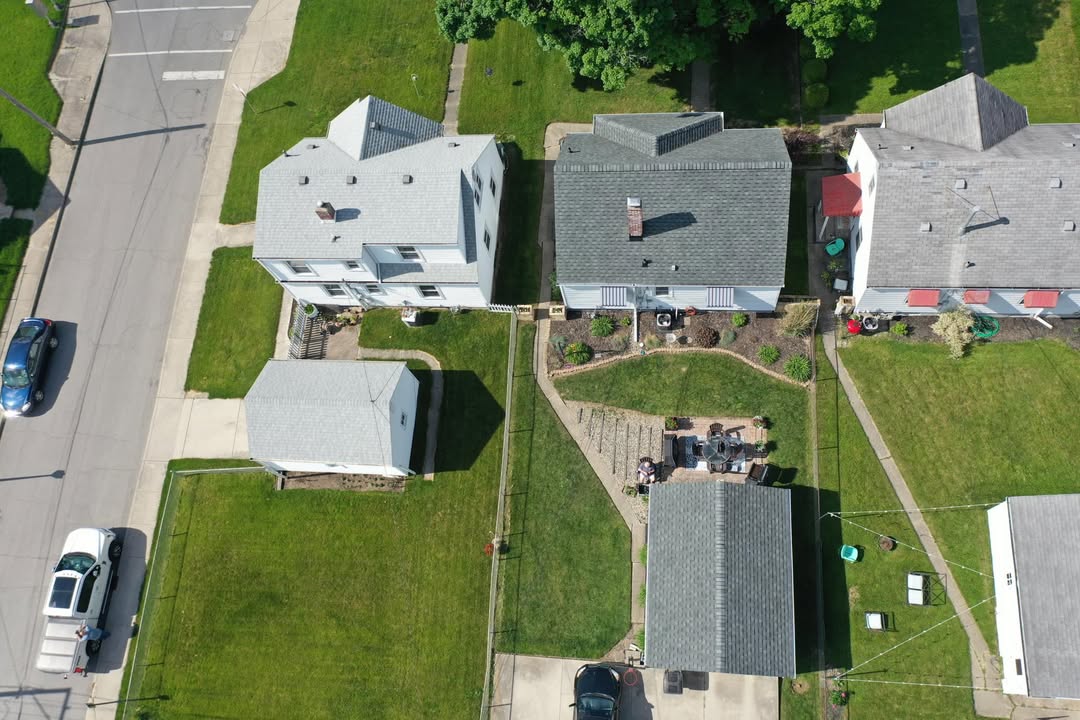 Aerial view of a home and detached garage with newly installed shingle roofs and seamless gutters by Affordable Roofing