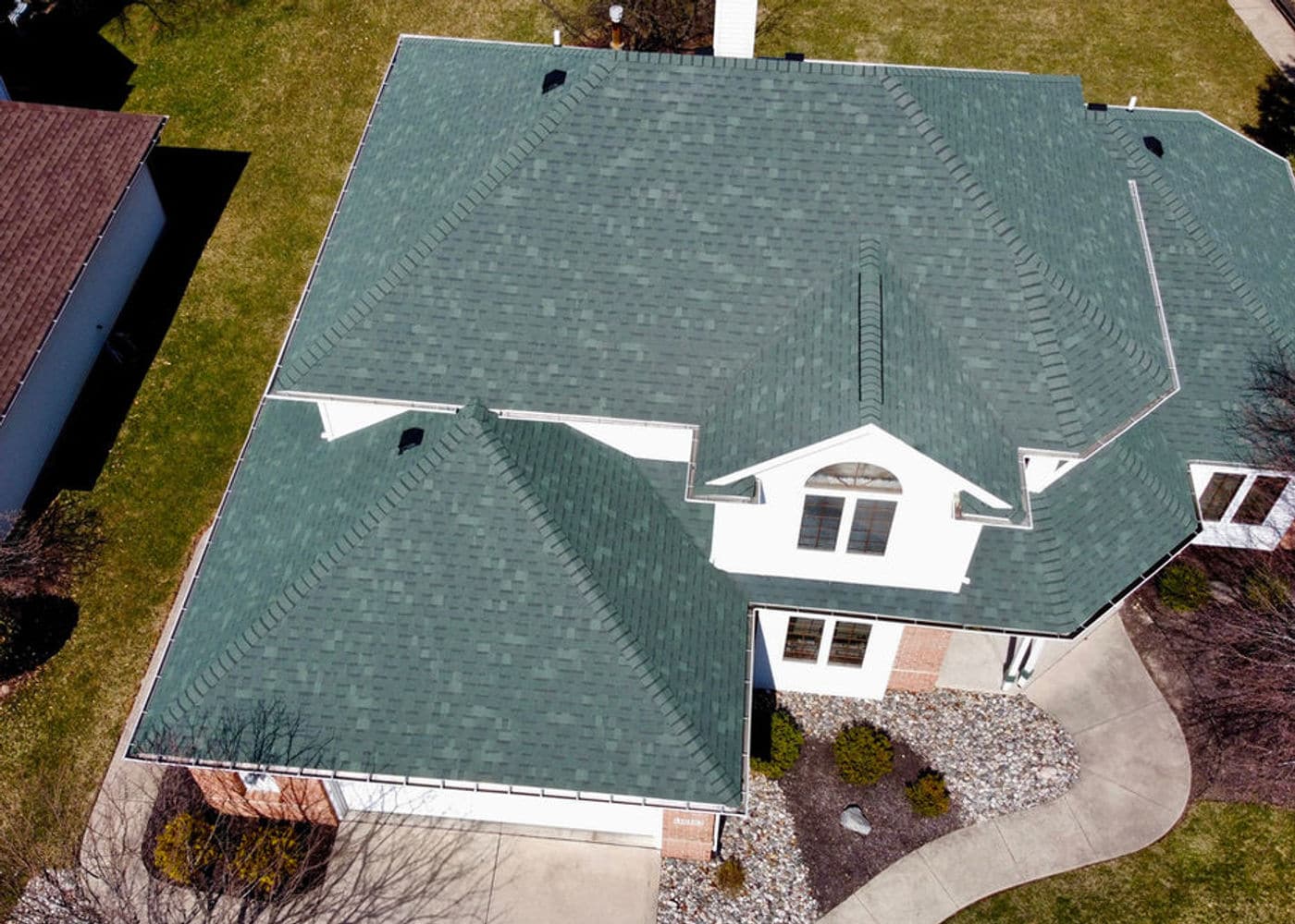 Green shingle roof surrounding a dormer above a landscaped front yard