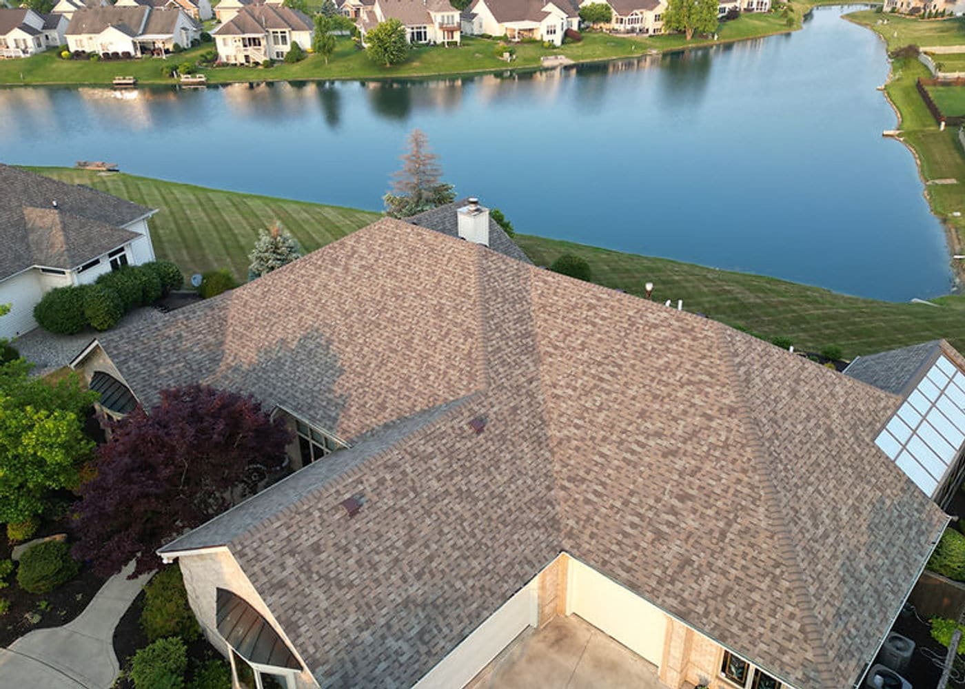 Brown shingle roof on a lakeside home beside neighboring properties