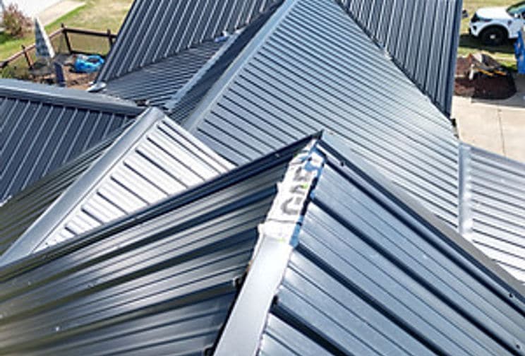 Intersecting roof ridges covered in dark standing seam metal panels
